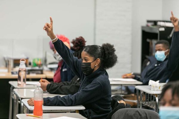 Kids in classroom raising their hands